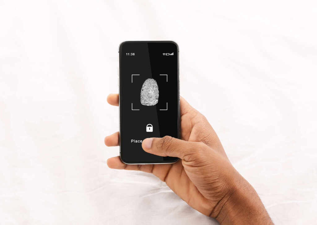 Identification Concept. Above Top View Of Black Man Holding Cellphone In Hand, Showing Application For Fingerprint Scanning With A Zone To Touch With Thumbprint Icon On The Gadget Screen